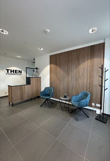 Moderne Empfangshalle mit Holzverkleitung, blauen Sesseln und minimalistischer Einrichtung.