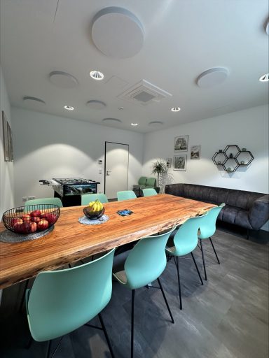 Modern Büroraum mit einem großen Holztisch, Stühlen und einer gemütlichen Couch.